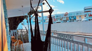 Ein Balkon mit einer Hängematte, einem Blumentopf und Blick auf farbenfrohe Gebäude.