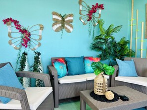 Una habitación con muebles de mimbre, una pared verde azulado y mariposas decorativas.