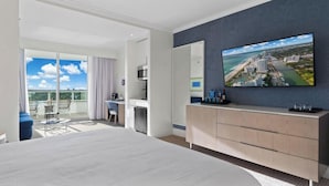 Et moderne hotelværelse med en stor seng, et skrivebord med stol, et fladskærms-tv og en balkon med udsigt.
