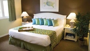 Ein ordentlich eingerichtetes Hotelzimmer mit einem Bett, zwei Nachttischen, einer Topfpflanze und einem gerahmten Bild an der Wand.