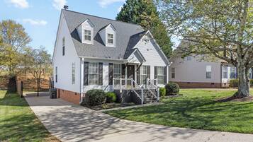 A two-story house with a front porch, a chimney, and a well-maintained lawn.