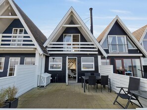 Et rækkehus med tre etager og en fælles patio med udendørs møbler.