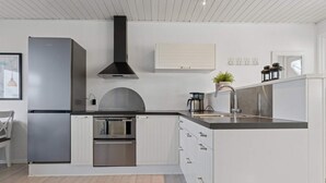 Una cocina moderna con horno empotrado, electrodomésticos de acero inoxidable y muebles de color blanco.