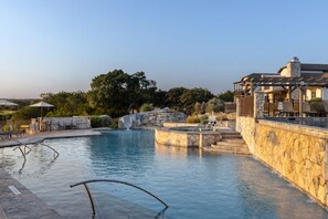 Une piscine avec des murs en pierre, une cascade et un espace salon abrité.