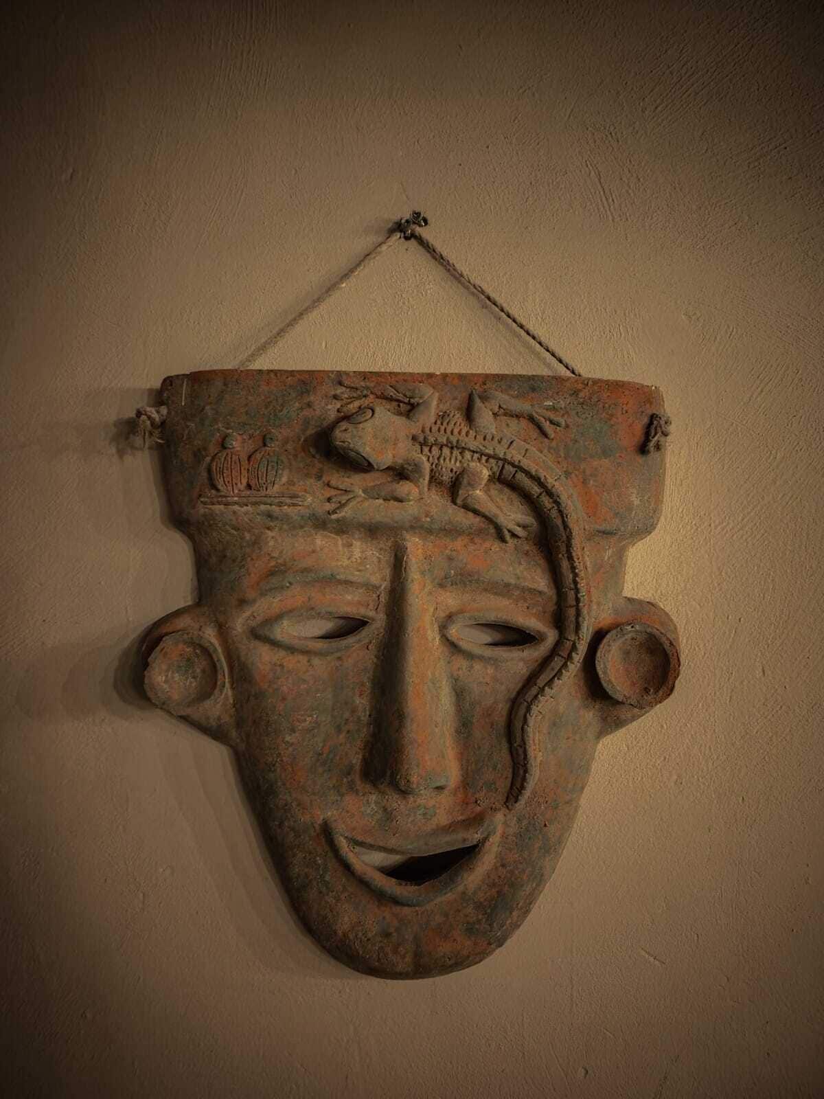 Een wandsculptuur met een gezicht, een vogel en een slang.
