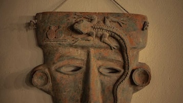 Een wandsculptuur met een gezicht, een vogel en een slang.