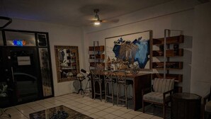 A living room with a dining area, a ceiling fan, a large abstract painting, and a closed door with a sign.