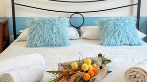 Un lit bien fait, avec des oreillers moelleux, un bouquet de fleurs et des serviettes pliées.