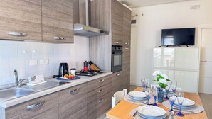 Une cuisine moderne équipée d’une cuisinière intégrée, d’un four et d’un téléviseur à écran plat fixé au-dessus des meubles de rangement.