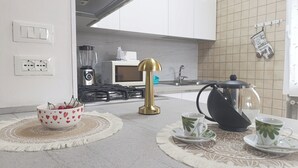 Eine moderne Küche mit einem Gaskochfeld, einer Kaffeemaschine und einem Wasserkocher auf der Arbeitsfläche.