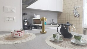 Una cucina moderna con un piano cottura a gas, una macchina del caffè e un bollitore sul bancone.