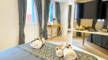 Une chambre d’hôtel avec un lit, un bureau, une télévision et une fenêtre avec des rideaux.