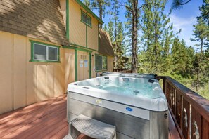 Ein Whirlpool auf einer Holzterrasse, im Hintergrund ein Haus.