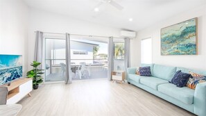 Una sala de estar moderna con un sofá azul claro, un ventanal que da al exterior, una pequeña mesa y un cuadro en la pared.