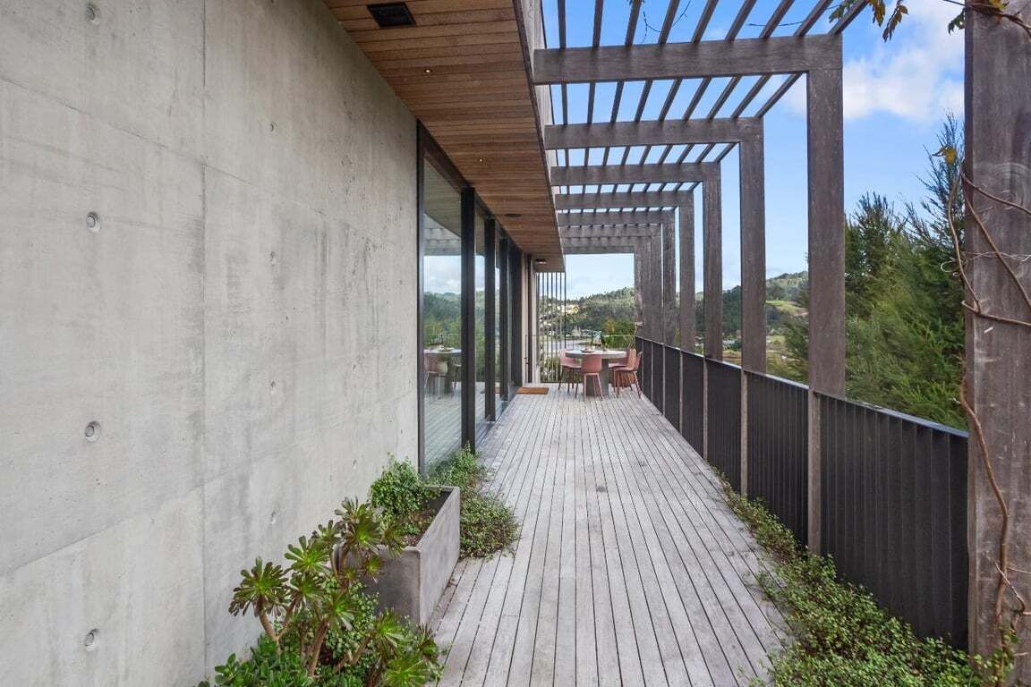 A wooden deck with a pergola, outdoor seating, and a view of the landscape.
