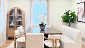 Een eetruimte met een houten tafel, comfortabele stoelen, een kast en een potplant.