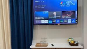 A flat-screen TV mounted on a wall displaying the Milan Cortina Olympics and NBC logo. - Sanrai (Gros Islet)