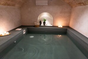 Une salle de spa équipée d’un bain à remous, de bougies et d’une petite plante.