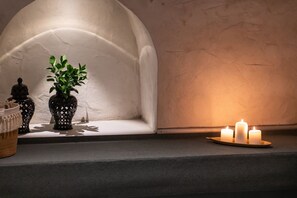Un intérieur chaleureux avec une alcôve blanche en forme d’arche, des vases noirs décoratifs, une plante en pot et des bougies disposées sur un plateau.