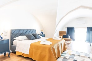 Une chambre d’hôtel moderne, équipée d’un lit, d’une chaise, d’une table de chevet et d’une grande fenêtre.