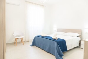 A hotel room with a bed, a chair, a nightstand, and a window with curtains. - Dimora Mennule Mare - Salento Reservation (Alliste)