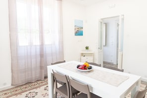 A room with a dining table, chairs, a small plant, and a painting on the wall. - Dimora Mennule Mare - Salento Reservation (Alliste)