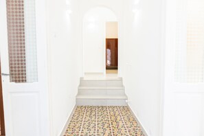 A hallway with a tiled floor leading to a room with a wooden door. - Dimora Mennule Mare - Salento Reservation (Alliste)