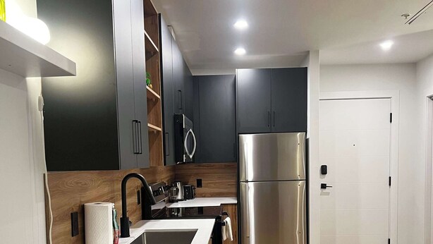 A modern kitchen with a stainless steel refrigerator, wooden cabinets, a built-in oven, and a sink. - A Vibrant Downtown Retreat for Groups, The Gallery (Halifax)