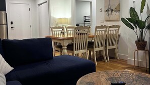 A living room with a sofa, dining table, chairs, a coffee table with a map design, and a potted plant. - A Vibrant Downtown Retreat for Groups, The Gallery (Halifax)