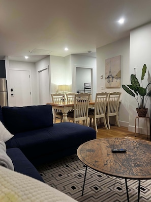 Ein Wohnzimmer mit einer Couch, einem Esstisch, Stühlen, einem Couchtisch mit Weltkarten-Design und einem Topf mit Pflanze.
