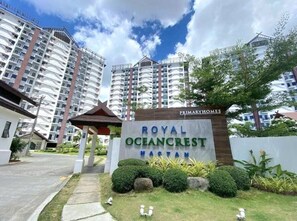 Naamplaatje voor Royal Oceancrest, een meerlaags wooncomplex met een heldere lucht en groen in de omgeving.