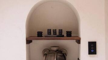 A wall with a shelf displaying small items and a large vase.