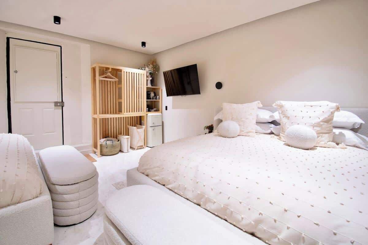 Un dormitorio con una cama grande, un armario, un televisor y una puerta.