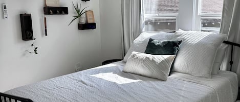 A bedroom with a bed, a ceiling fan, a window with curtains, and wall-mounted shelves.