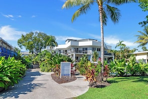 A hotel with a sign indicating no vacancies, surrounded by lush greenery and palm trees.