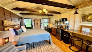 Ein Schlafzimmer mit Bett, Nachttisch, Lampe und Blick ins Freie.