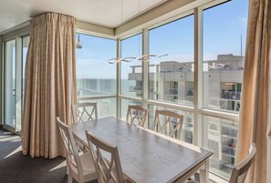 Habitació d'hotel amb balcó, taula de menjador i cortines.