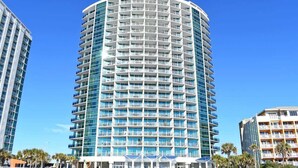 A multi-story hotel with a curved facade, numerous balconies, and a clear blue sky in the background. - Large 2BR at Oceans One Resort  with Best Ocean View (Myrtle Beach)