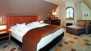 Camera d'albergo con un letto grande, una scrivania, una sedia, un divano e una finestra con tende.