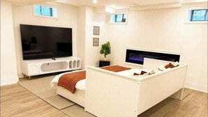 Un dormitorio moderno con cama, televisión, chimenea y ventana.