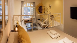 Et moderne interiør med sofa, spisebord, trappe og et tv på væggen.