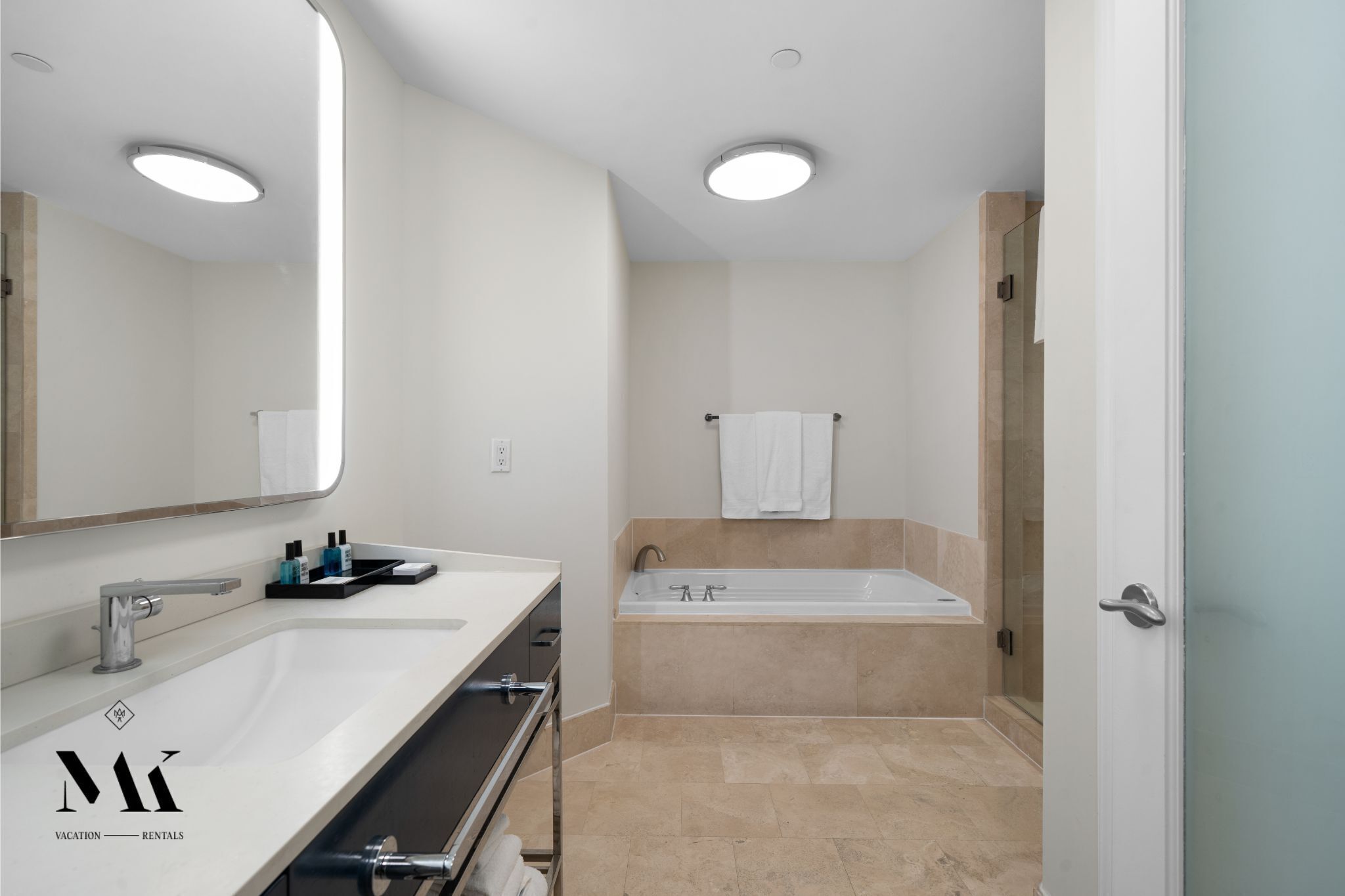 A modern bathroom with a large mirror, a sink, a bathtub, and a shower.