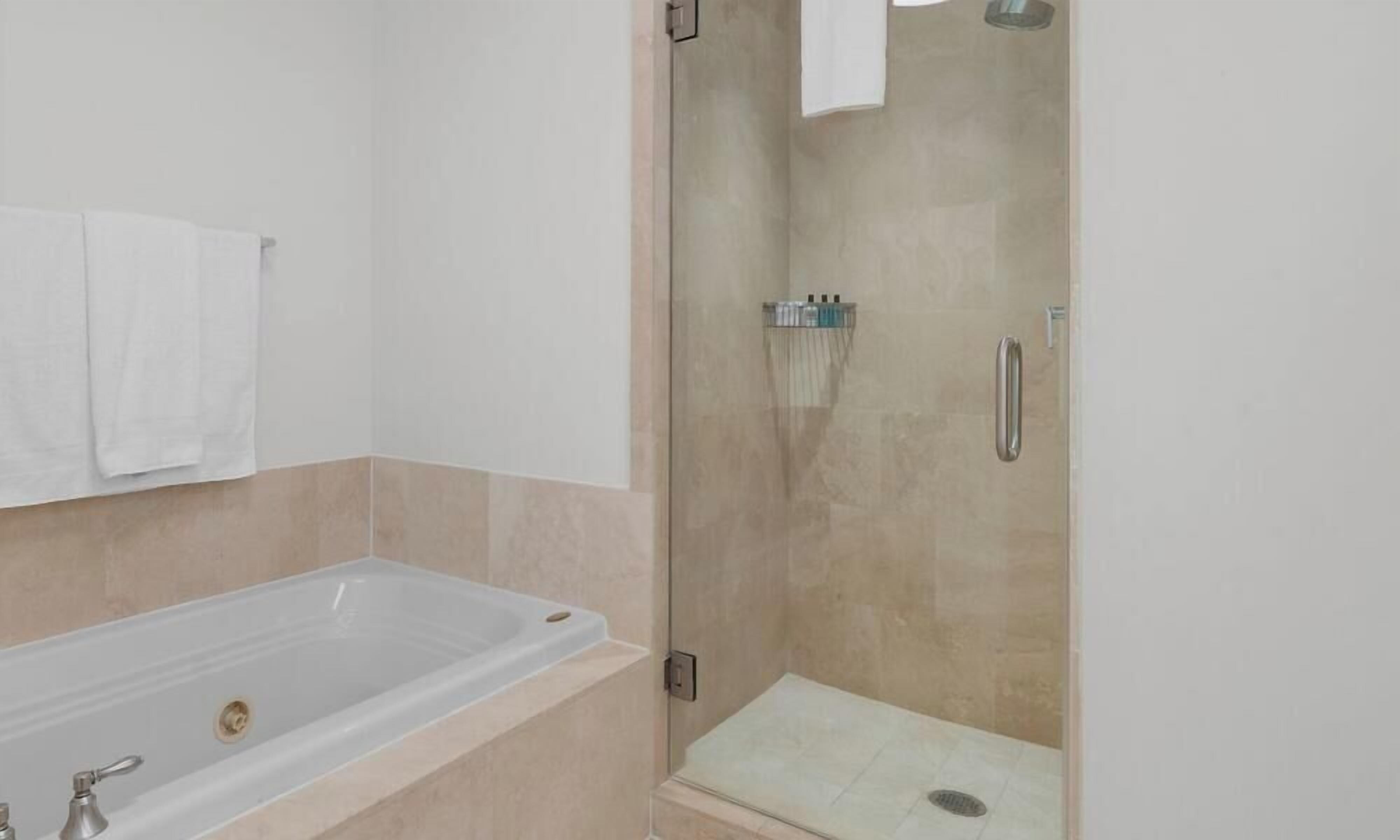 A modern bathroom with a bathtub, a glass-enclosed shower, and a towel rack.