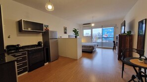Eine moderne Küche mit Herd, Kühlschrank und Essbereich inklusive Tisch und Stühlen.