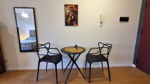 Een kamer met een bed, een spiegel, een schilderij, een telefoon en twee stoelen rondom een tafeltje.