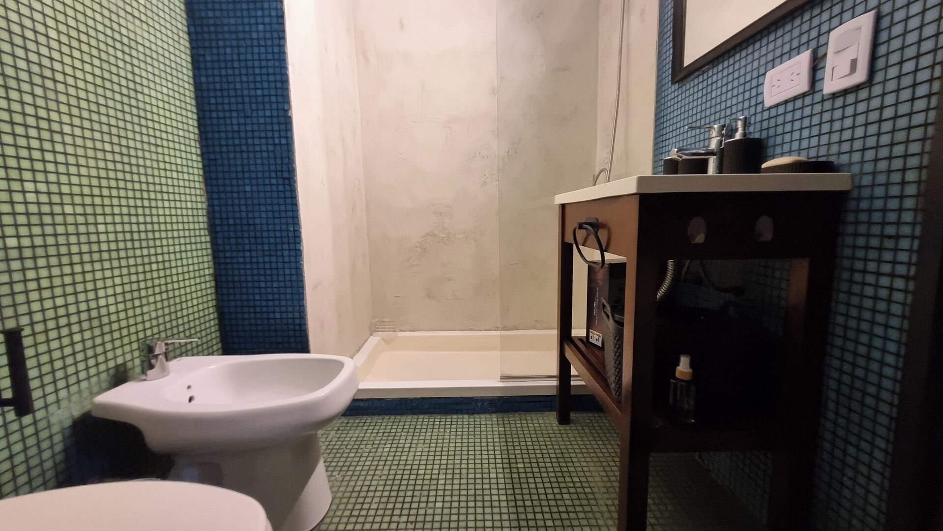 A bathroom with a bidet, a toilet, a bathtub, and a vanity with toiletries.
