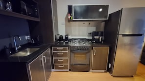 Une cuisine de taille réduite équipée d’une cuisinière, d’un four, d’un évier et d’un réfrigérateur.