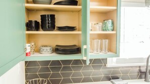 A kitchen with teal cabinets, black and white plates, and a tiled backsplash. - Bardstown Bourbon Royale, Just 1 block from Downtown Historic District (Bardstown)