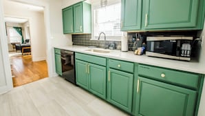 A kitchen with green cabinets, a dishwasher, a sink, a microwave, and a window with blinds. - Bardstown Bourbon Royale, Just 1 block from Downtown Historic District (Bardstown)