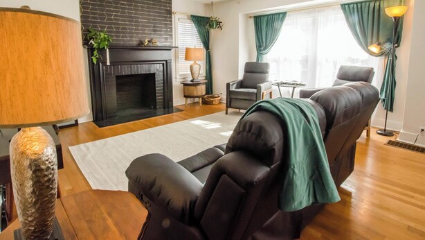 A living room with a fireplace, leather sofa, armchair, and a lamp. - Bardstown Bourbon Royale, Just 1 block from Downtown Historic District (Bardstown)